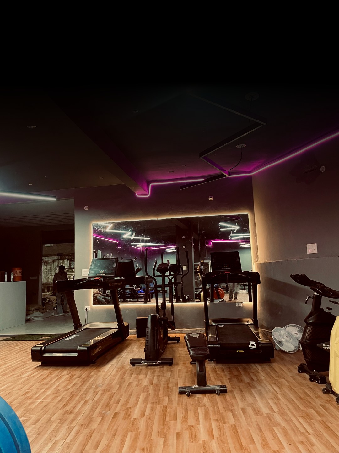 DreamFit gym floor in Manoharpur, Shahpura — treadmills, cardio machines and illuminated mirror under magenta LED lighting